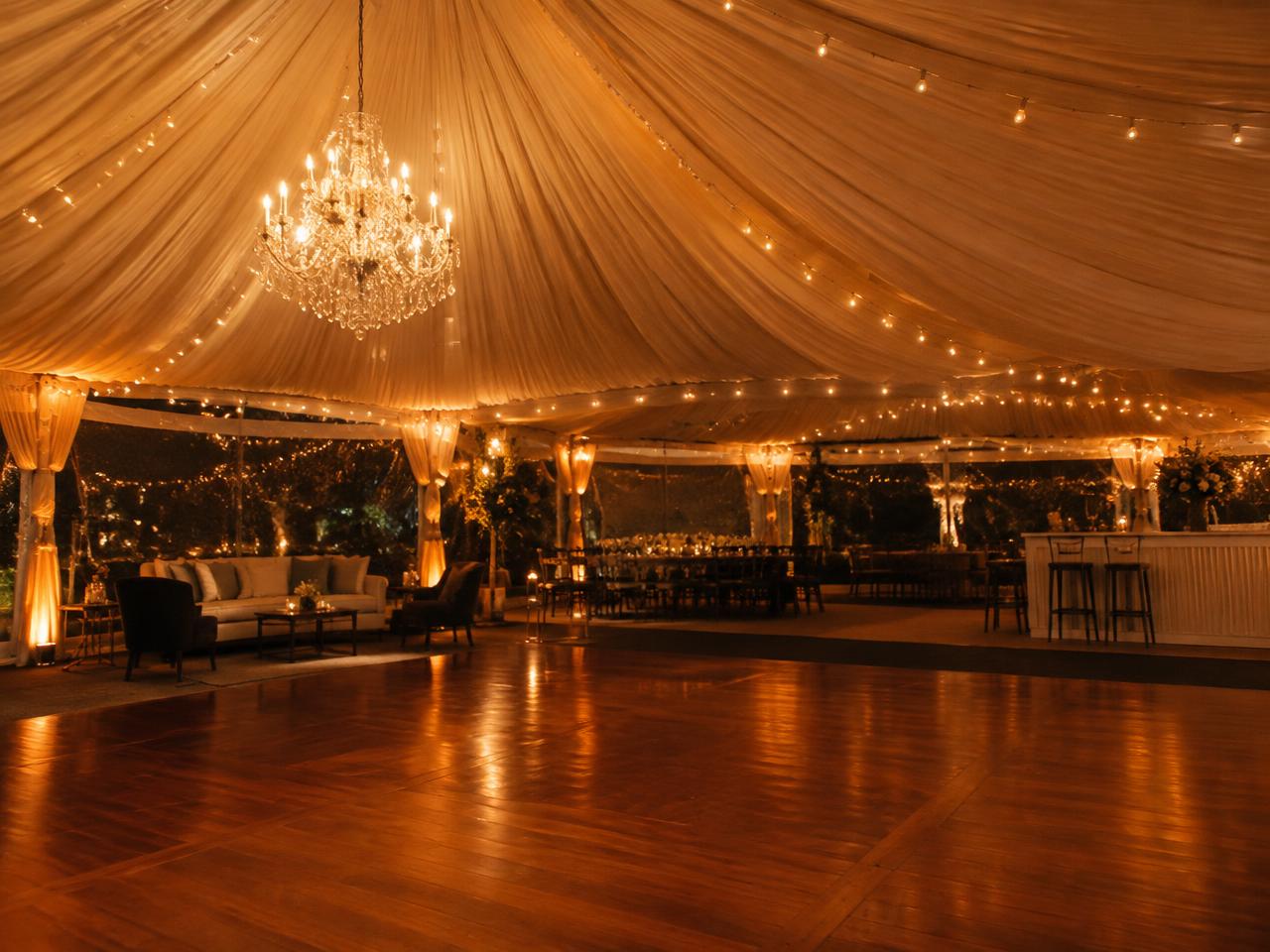 Dance floor and chandelier inside a draped marquee